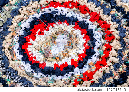 Vintage homespun doormat made from strips of cloth as background. Texture of a homemade rug from different fabrics. Round knit mat Vintage homespun doormat made from strips of cloth as background. Texture of a homemade rug from different fabrics. Round knit mat 132757543