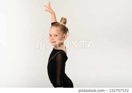 Smiling child in black ballroom outfit practicing elegant movement with hearing technology cochlear implant. Copy space. Strength, inclusion, and artistic discipline harmonize to celebrate diversity 132757552