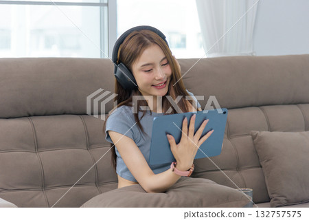 Young woman happy at home, people enjoy leisure activity, listening music on headphones with tablet, smiling expression shows relaxation, connection, engaging with digital content. Young woman happy at home, people enjoy leisure activity, listening music on headphones with tablet, smiling expression shows relaxation, connection, engaging with digital content. 132757575