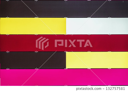 Striped wall with alternating colorful horizontal metal panels in red, yellow, pink, white, black tones. Modern design, urban decorative color palette 132757581