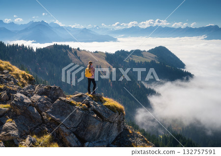 Woman with backpack on mountain ridge above a sea of clouds Woman with backpack on mountain ridge above a sea of clouds 132757591