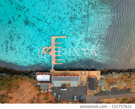 Aerial view of wooden pier, azure water, houses on the sea coast Aerial view of wooden pier, azure water, houses on the sea coast 132757622