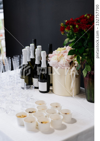 Table setup with champagne bottles, glasses, and flower bouquets prepared for celebration Table setup with champagne bottles, glasses, and flower bouquets prepared for celebration 132757700