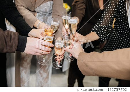 Group of people toasting with champagne glasses at festive celebration or corporate event 132757702