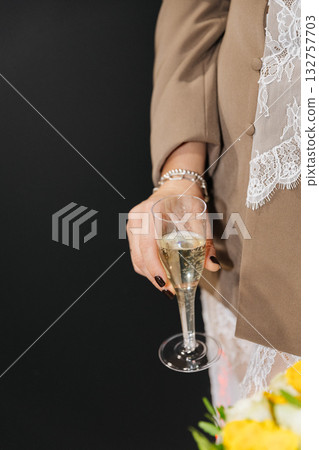 Elegant woman holding champagne glass in hand wearing lace outfit at festive event 132757703