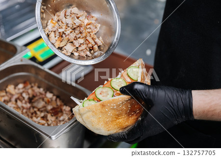 Chef preparing shawarma sandwich with grilled meat and fresh vegetables in pita bread 132757705