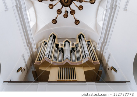 Grand church organ pipes under vaulted ceiling with elegant chandelier, interior architecture 132757778