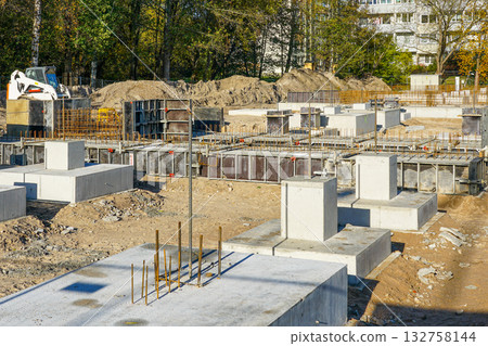 Apartment building concrete foundations with steel reinforcement under construction at urban site Apartment building concrete foundations with steel reinforcement under construction at urban site 132758144