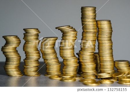 Leaning stacks of gold coins symbolizing financial instability, economic imbalance, and risk Leaning stacks of gold coins symbolizing financial instability, economic imbalance, and risk 132758155
