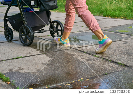 Legs of a young mother walking with a baby stroller Legs of a young mother walking with a baby stroller 132758298