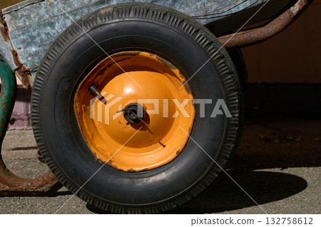 Old wheelbarrow rubber wheel with an orange rim 132758612