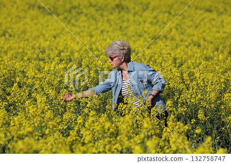 Female agronomist examining blossoming rapeseed field 132758747