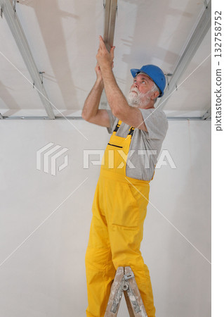 Senior adult worker fixing aluminum batten for gypsum ceiling 132758752