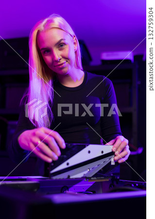Young Caucasian woman upgrades gaming PC in neon-lit setup, showcasing focus and tech skills 132759304