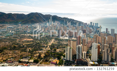 Panoram view of Benidorm showing its tall residential towers, beaches, and deep blue Mediterranean Sea. Vibrant resort city on the eastern coast of Spain. 132761259