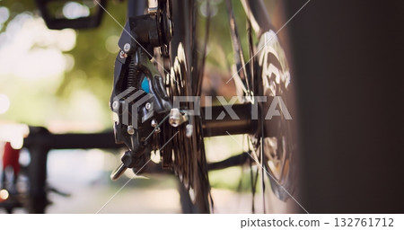 Close-up shot of various bicycle parts like cassette, pulley wheel and rear derailleur being maintained outside. Detailed view of person adjusting on broken bike wheel with specialized tool. 132761712