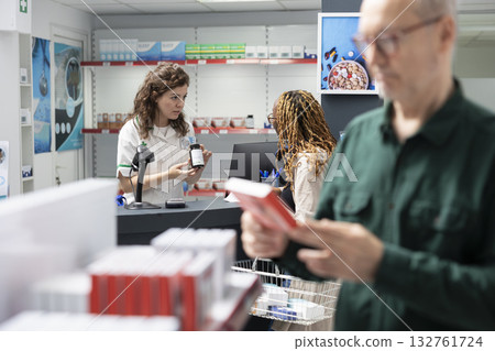 Senior man patient consults female cashier at the apothecary counter, receiving assistance with prescription medicine, dosage recommendation and the selection of pharmaceutical drugs. Senior man patient consults female cashier at the apothecary counter, receiving assistance with prescription medicine, dosage recommendation and the selection of pharmaceutical drugs. 132761724