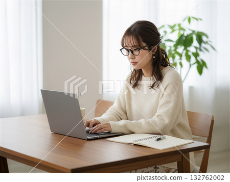 A smiling Japanese woman in her twenties operating a laptop at home: IT, learning, telework, lifestyle / AI 132762002