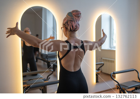 Woman with dreadlocks determined woman in black leggings performs pilates with focused energy Woman with dreadlocks determined woman in black leggings performs pilates with focused energy 132762113