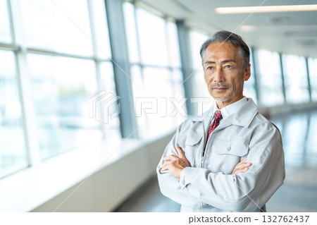 A man in work clothes with his arms crossed 132762437