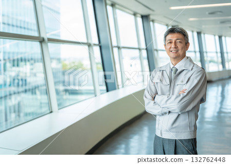 A man in work clothes standing in an office lobby 132762448