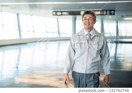 A man in work clothes standing in an office corridor 132762748