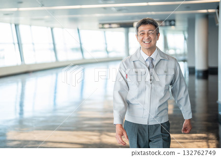 一名身著工作服的男子站在辦公室走廊裡 132762749