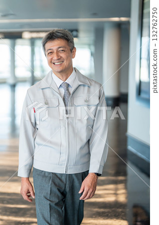 一名身著工作服的男子站在辦公室走廊裡 132762750