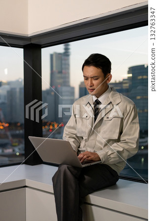 A man in work clothes operating a computer in an office A man in work clothes operating a computer in an office 132763347