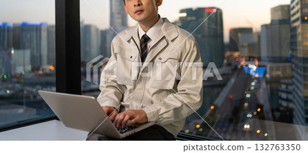 A man in work clothes operating a computer in an office A man in work clothes operating a computer in an office 132763350