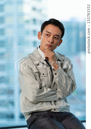 一個穿著工作服的男人雙手交叉，正在思考。 132763352