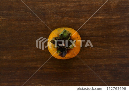 Distressed persimmons on a table in the background, seen from above 132763696