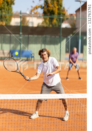 Two men playing lawn tennis outdoors Two men playing lawn tennis outdoors 132763761