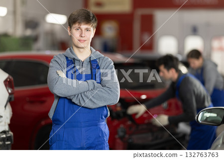 Service station young man employee works in repair box, department 132763763