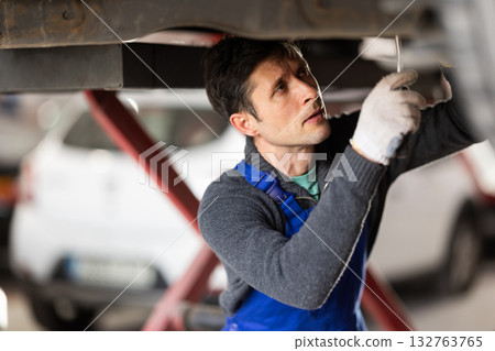 Service station man employee works in repair box, department 132763765