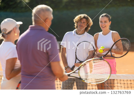 Group of friends or family spending time playing sports on tennis courts and talking during breaks Group of friends or family spending time playing sports on tennis courts and talking during breaks 132763769