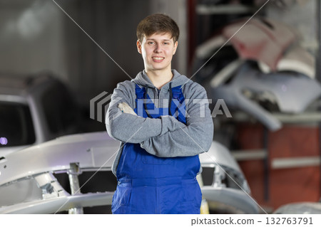 Service station young man employee works in repair box, department 132763791