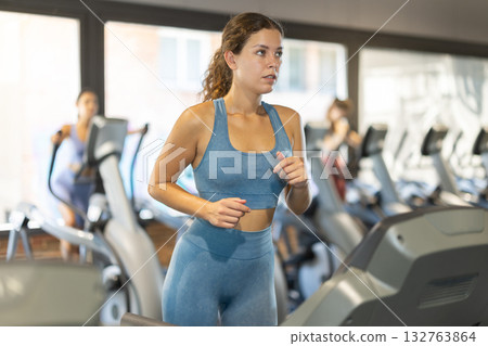 Sportive young girl training on treadmill in gym 132763864