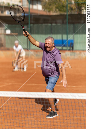 Elderly couple playing tennis together in court 132763885