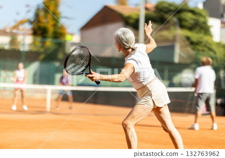 Elderly woman with racket in hands receiving pass Elderly woman with racket in hands receiving pass 132763962