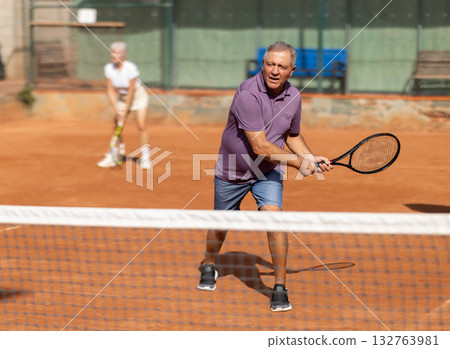 Elderly couple playing tennis together in court Elderly couple playing tennis together in court 132763981