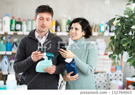 Couple man and woman scanning qr code for cleaning spray Couple man and woman scanning qr code for cleaning spray 132764003