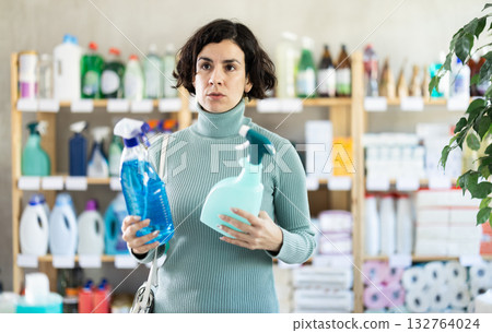 Adult woman chooses cleaning spray in store 132764024
