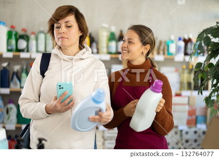 Young saleswoman offering detergent to female customer 132764077