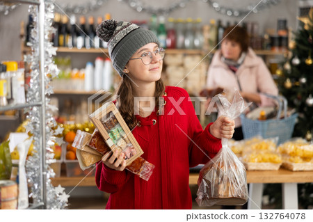 Adolescence girl customer choose consider desserts and sweet snacks, woman in background 132764078