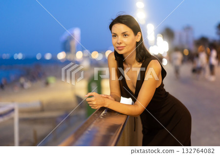 Young woman leaning on parapet at Barceloneta beach in summer evening 132764082