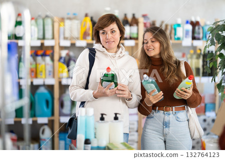 Mum with adult daughter purchases household chemicals in store, choose dishwashing detergent Mum with adult daughter purchases household chemicals in store, choose dishwashing detergent 132764123