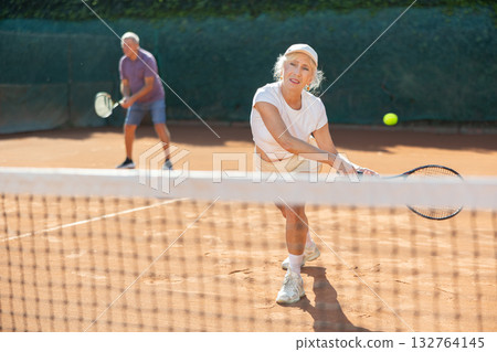 Elderly couple playing tennis together in court 132764145