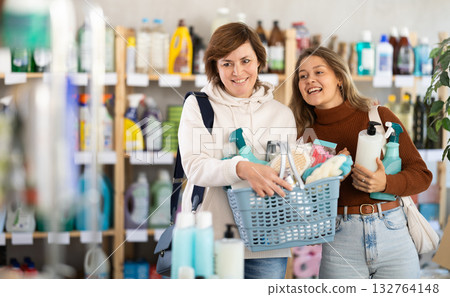 Women with filled basket wanders around store, looking at display cases and inspects assortment Women with filled basket wanders around store, looking at display cases and inspects assortment 132764148
