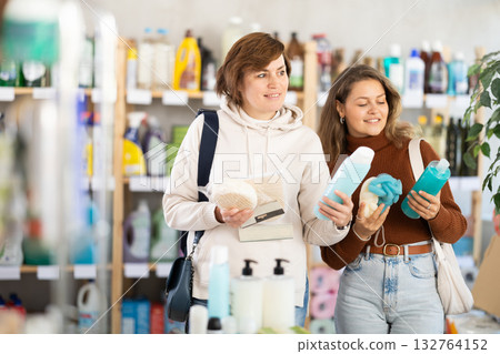Two women choose best shampoo or shower gel and body washcloth together in household supermarket Two women choose best shampoo or shower gel and body washcloth together in household supermarket 132764152